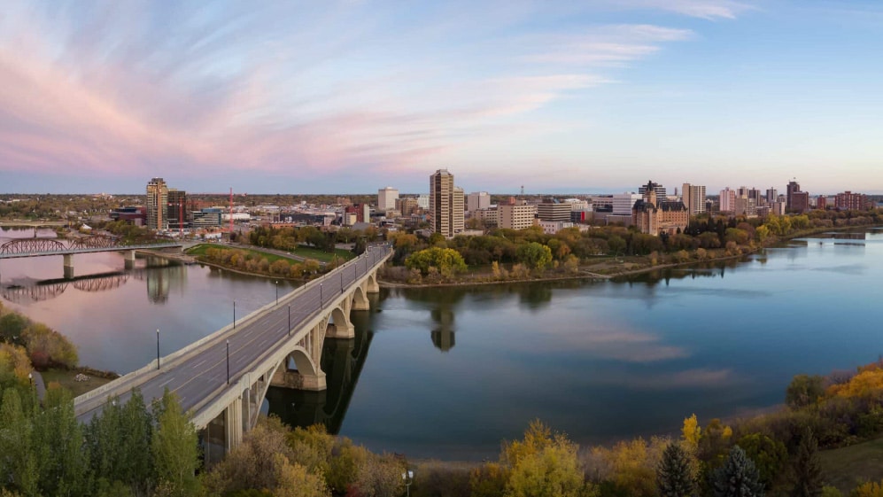 Aerial panoramic view of a bridge going over Saskatchewan River during a vibrant sunrise in the Fall Season. Taken in Saskatoon, SK, Canada.